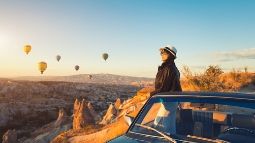 woman watching colorful hot air balloons flying over the valley at Cappadocia
