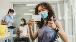 woman holding COVID-19 vaccination card